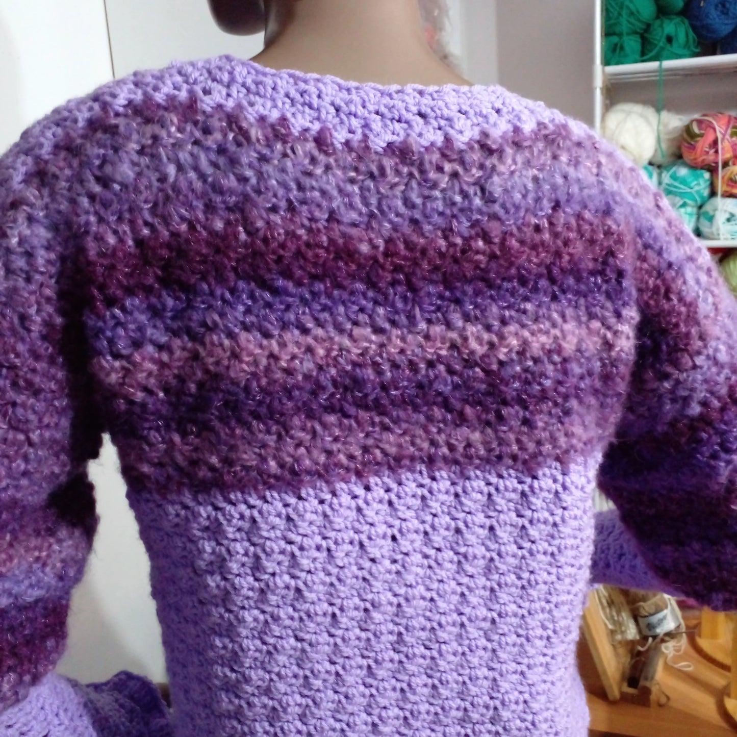Pull au crochet Fuga - vue de dos dans l'atelier avec pelotes de laine colorées