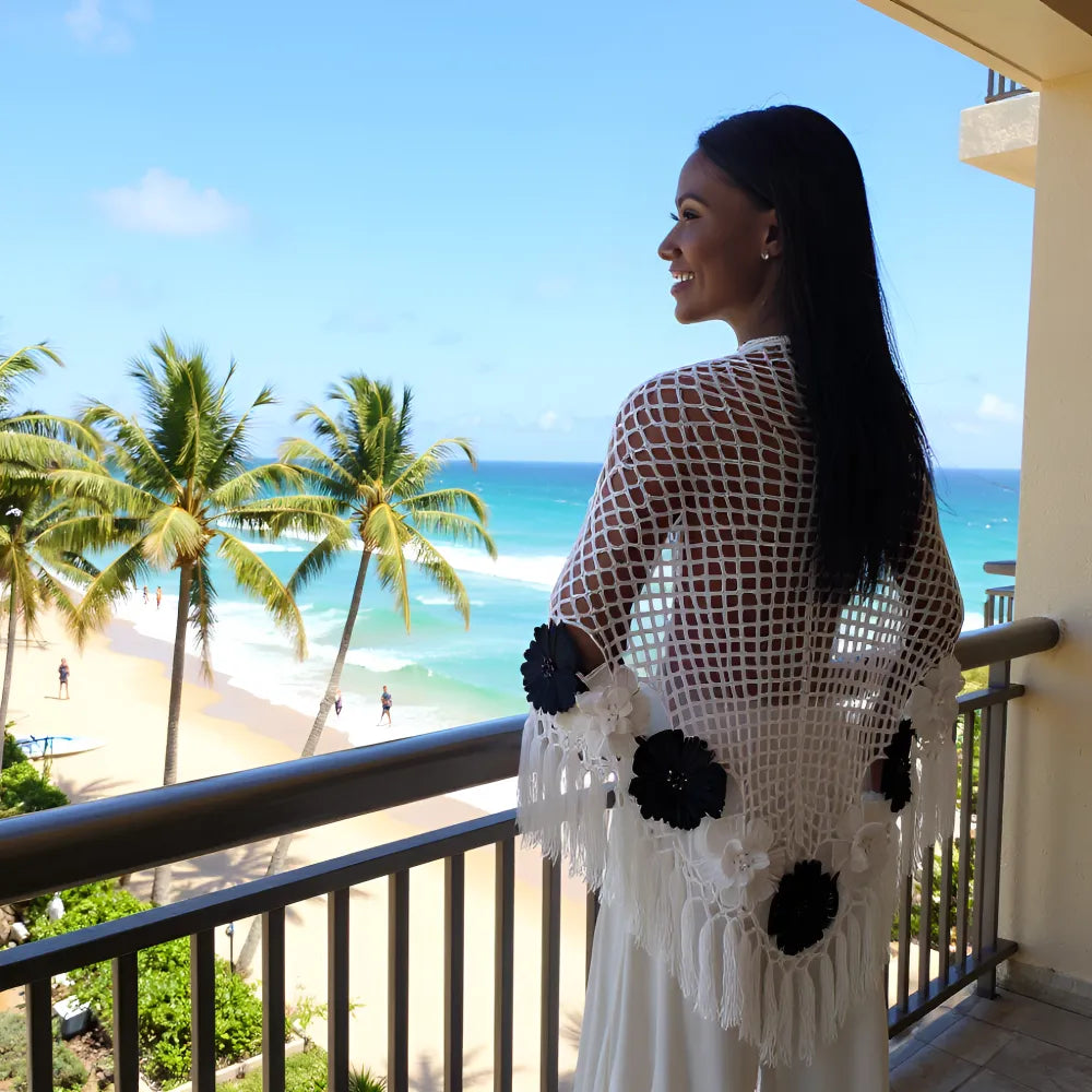 Châle au crochet Mozamba de Cachalabibi - vue de dos et porté par une jeune femme sur un balcon avec vue mer