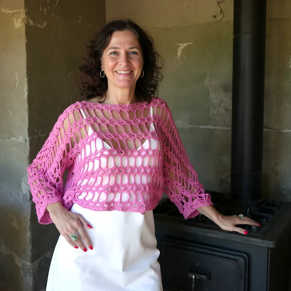 Chauffe-épaules au crochet Cétoudou de Cachalabibi - porté debout par une femme devant un vieux poêle à charbon