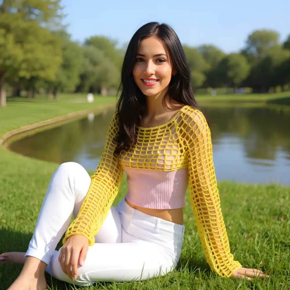 Crop top au crochet Napolitano de Cachalabibi - vue de face d'une jeune femme assise sur l'herbe devant un étang