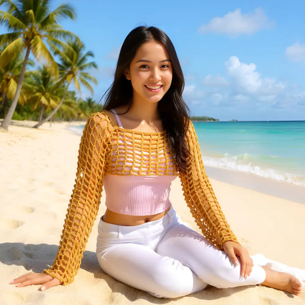 Crop top au crochet Sweetie de Cachalabibi  - jeune femme assise sur une plage tropicale déserte