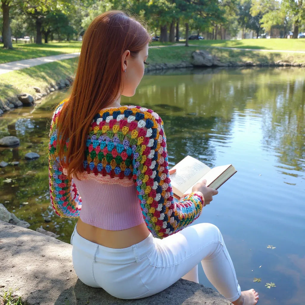 Crop top au crochet Volarino de Cachalabibi - vue de dos en lecture au parc au bord du lac