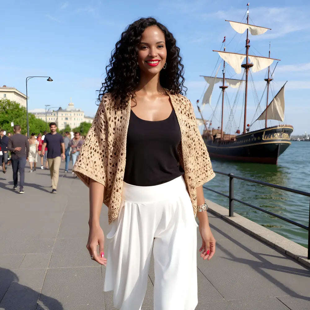 Gilet au crochet Albatros de Cachalabibi -porté par une jeune femme près d'un fleuve avec un vieux gréement en arrière-plan