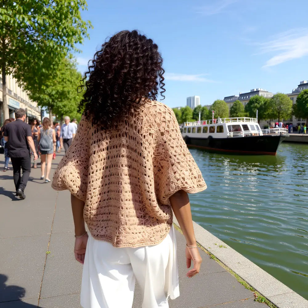 Gilet au crochet Albatros de Cachalabibi - vue de derrière sur une jeune femme aux cheveux bruns près d'un quai de Seine