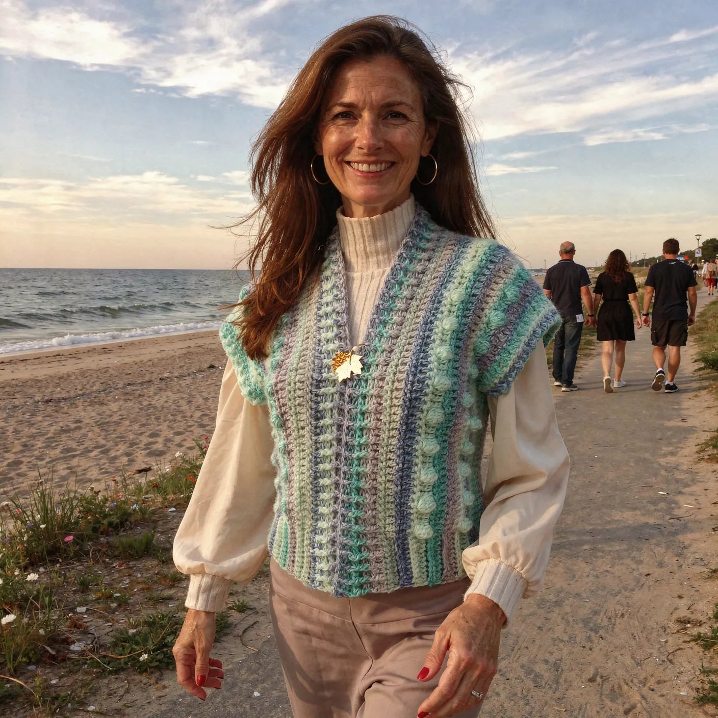 Gilet au crochet Pastello de Cachalabibi -
vue de face sur une promenade en bord de mer au coucher du soleil avec plage et promeneurs