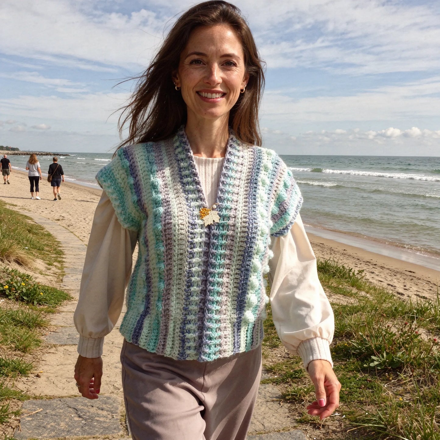 Gilet au crochet Pastello de Cachalabibi -vue de face sur une promenade en bord de mer avec plage et promeneurs