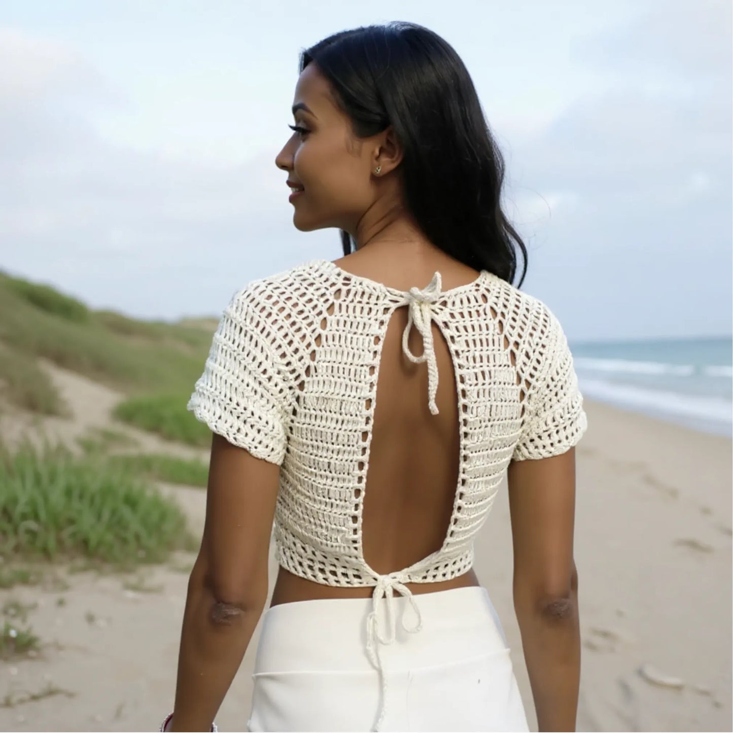 Haut au crochet Bianco de Cachalabibi -vue de dos sur une plage d'une jeune femme  en pantalon blanc