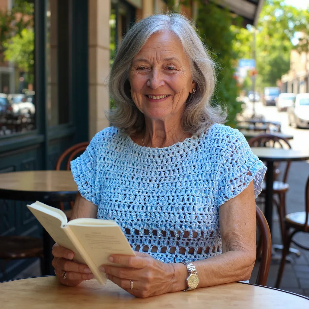 Haut au crochet Brunnera de Cachalabibi - vue de face d'une dame âgée qui lit un livre en terrasse