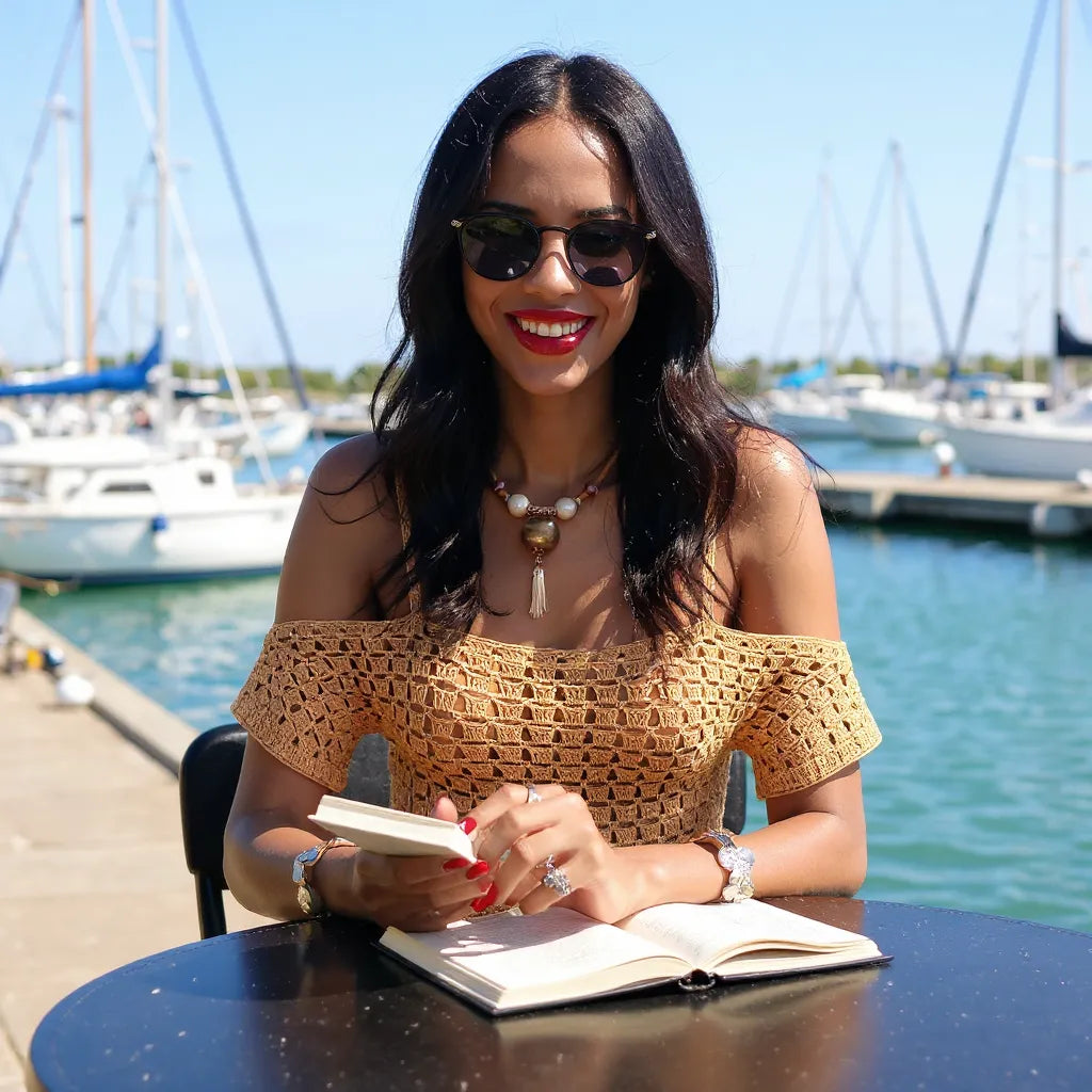 Haut au crochet Caramella de Cachalabibi - jeune femme en lecture au bord d'un port de plaisance
