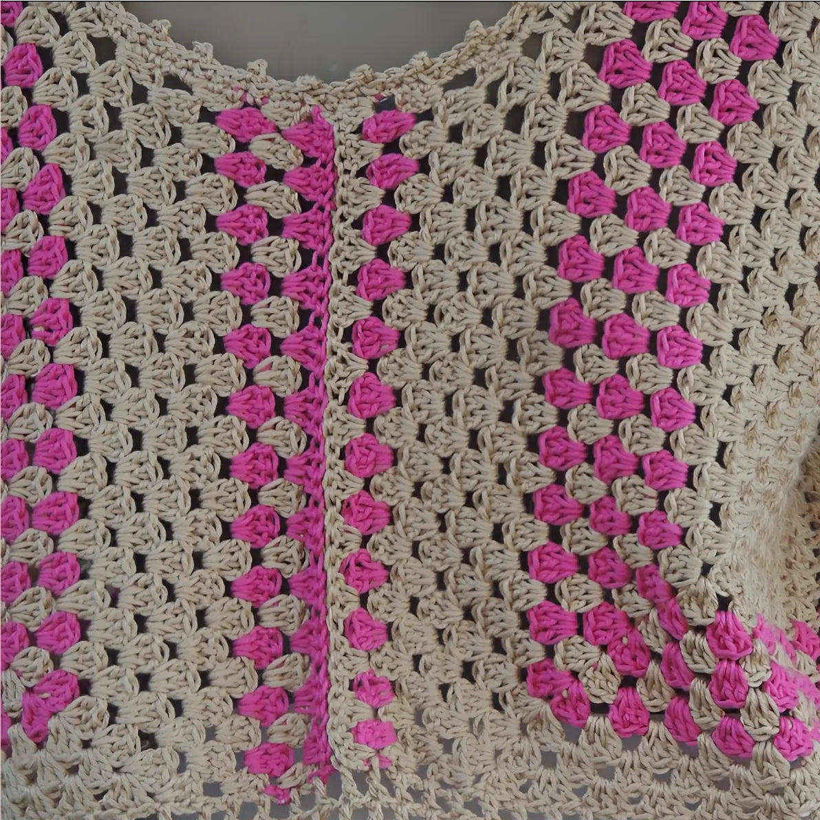 Haut au crochet Cremarosa de Cachalabibi - gros plan du détail de l'encolure en V et des motifs géométriques roses du haut Crémarosa