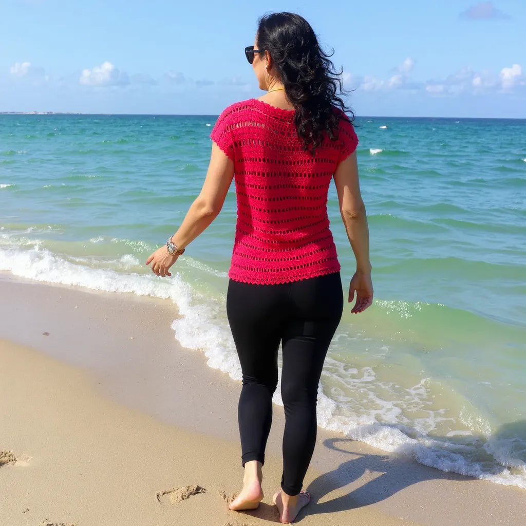 Haut au crochet Granada de Cachalabibi - vue de dos d'une jeune femme en pantalon noir à la plage