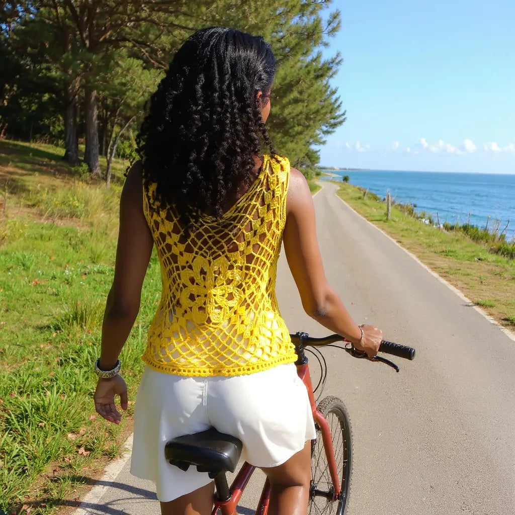 HautHaut au crochet Narcisola de Cachalabibi - vue de dos d'une jeune femme à vélo sur une piste longeant la mer