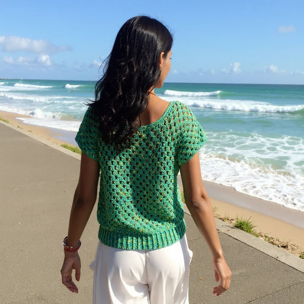 Haut au crochet Papayo de Cachalabibi - vue de dos d'une jeune femme marchant au bord de la mer