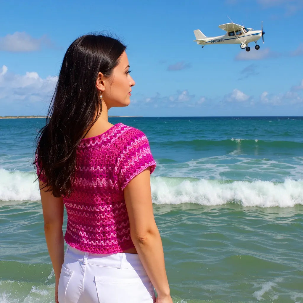 Haut au crochet Pitaya de Cachalabibi - vue de trois-quarts à la plage d'une jeune femme avec le survol d'un avion