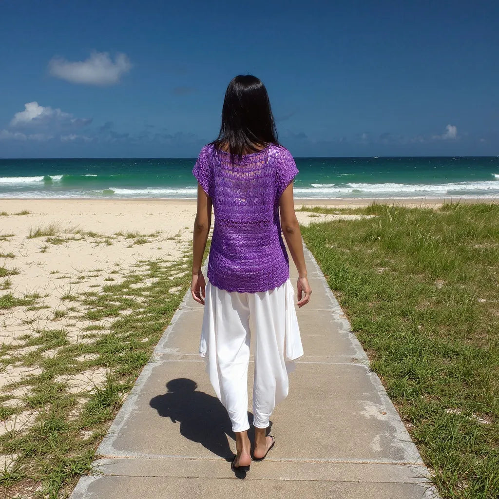 Haut au crochet Violeta de Cachalabibi -Vue de dos d'une femme marchant sur un sentier menant à la plage