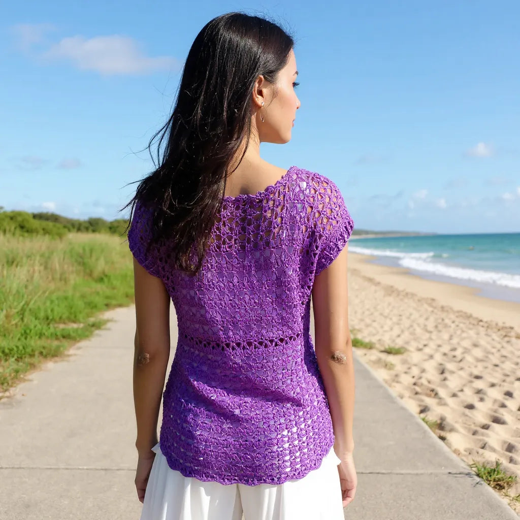 Haut au crochet Violeta de Cachalabibi - vue de dos d'une jeune femme brune sur une piste longeant le bord de mer