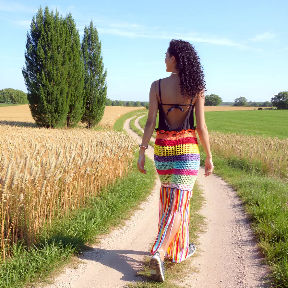 Jupe longue au crochet Arcobaleno arc-en-ciel avec franges portée de dos en promenade eprès d'un champ de blé