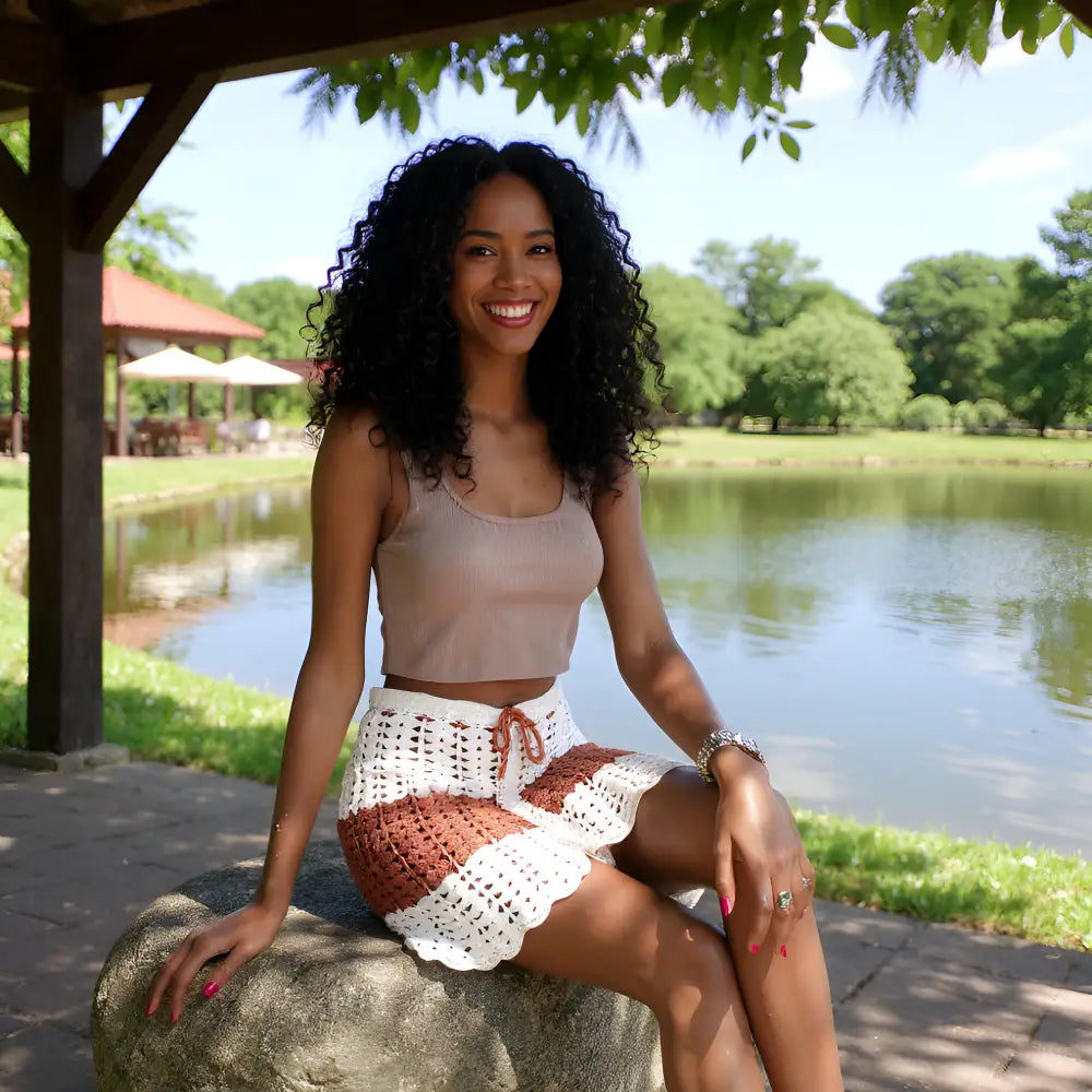 Jupe au crochet Cappuccina écru et caramel portée assise sur une pierre deant un étang