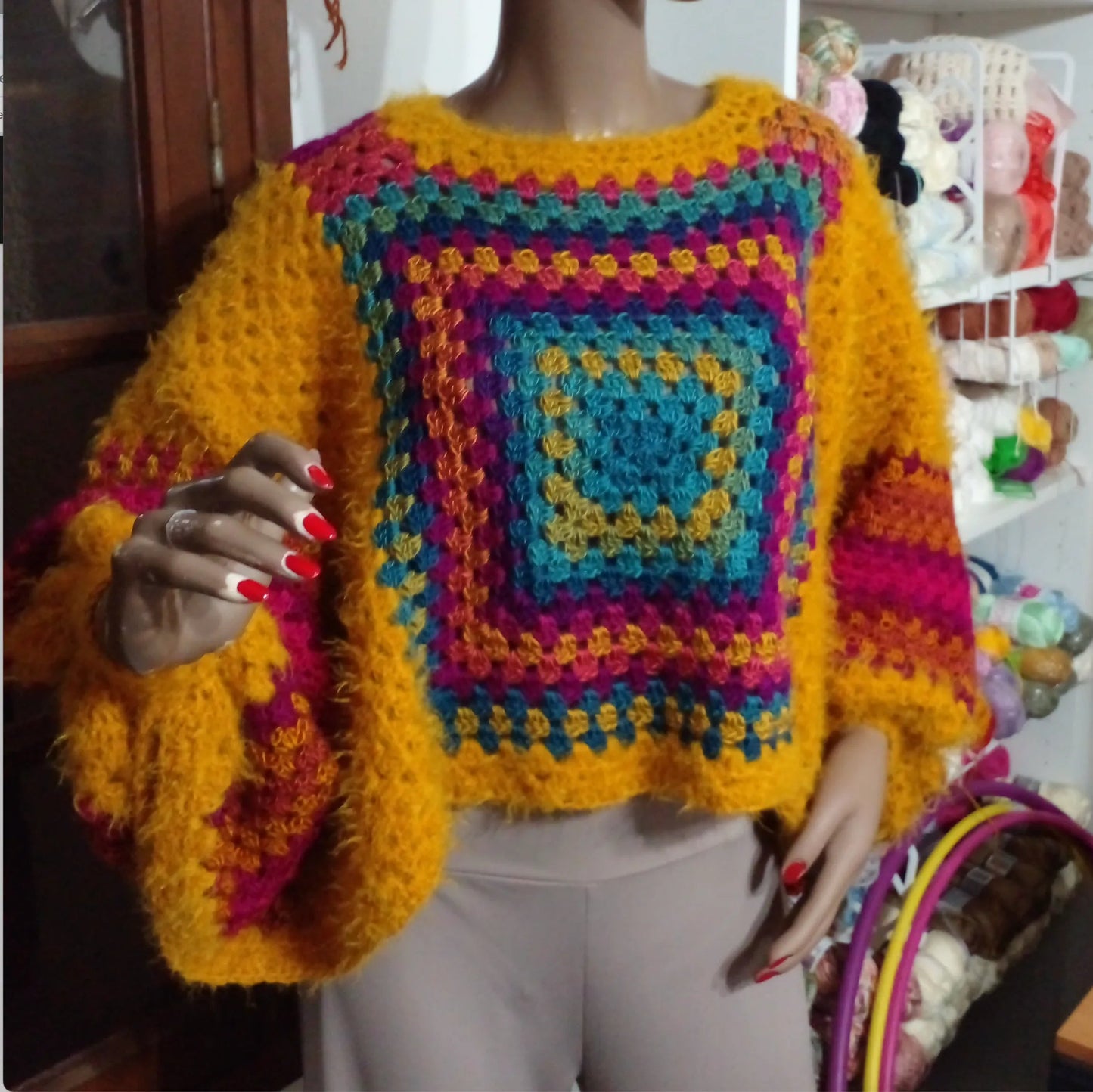 Poncho au crochet Aranciano de Cachalabibi - gros plan de face du poncho sur un mannequin et pelotes de laine colorées