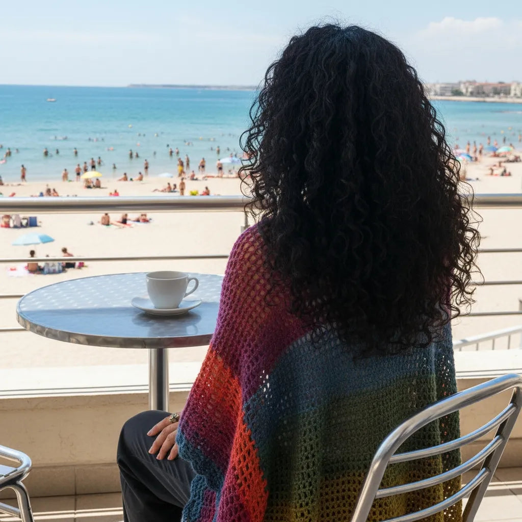Poncho Makun arc-en-ciel multicolore avec dégradé - vue de dos à la terrasse d'un café de plage avec vue sur l'océan