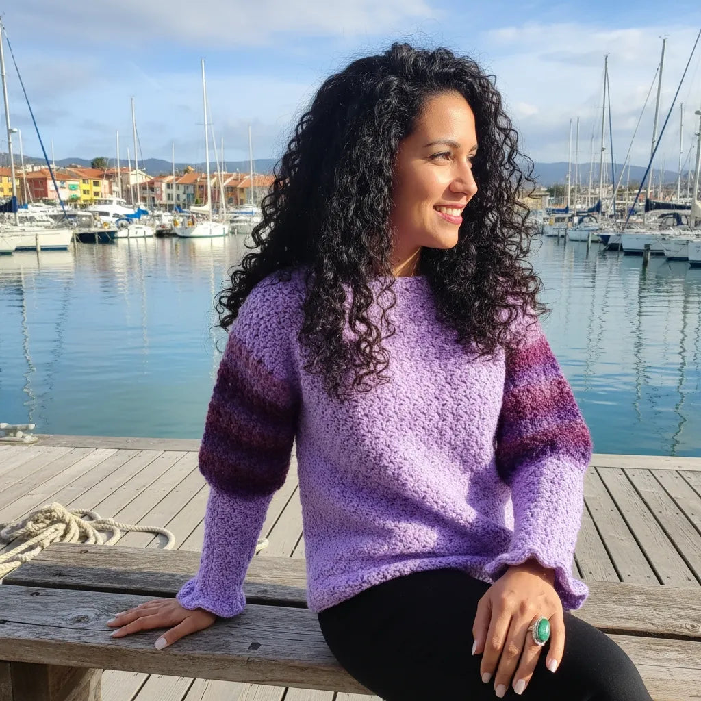 Pull au crochet Fuga dégradé horizontal violet lilas lavande - vue de profil assise sur un banc à la marina avec voiliers
