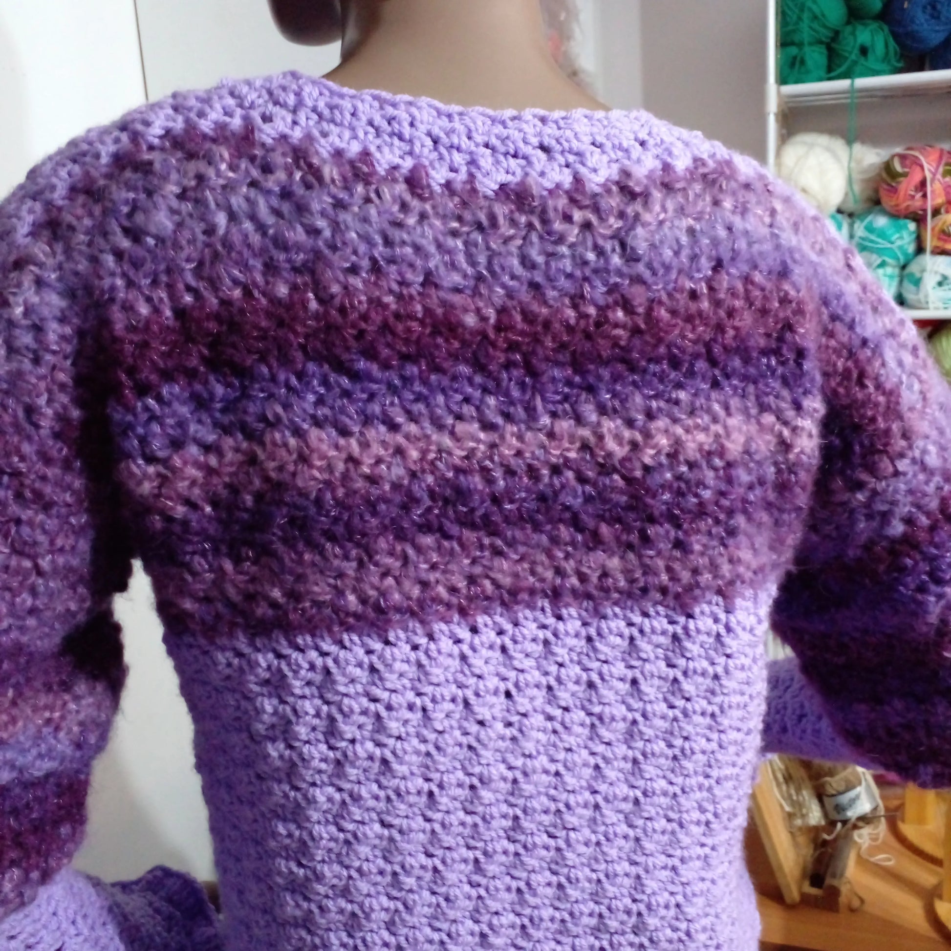 Pull au crochet Fuga - vue de dos dans l'atelier avec pelotes de laine colorées