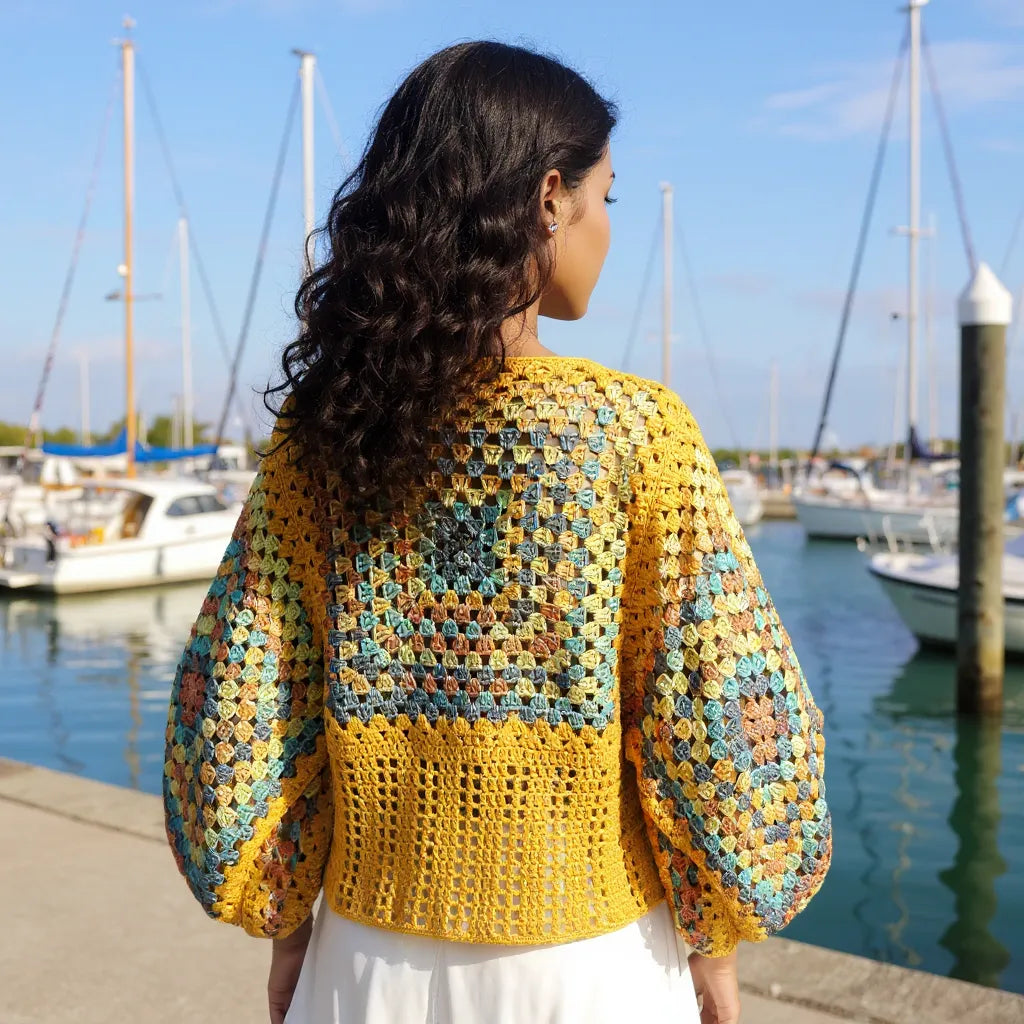 Pull au crochet Labyrintho de Cachalabibi - Dos coloré avec des manches amples sur une femme dans une marina