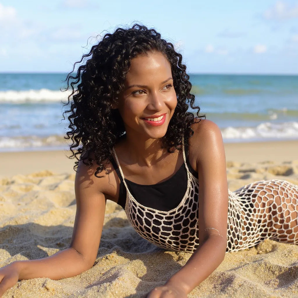 Robe de bain au crochet Bellarete de Cachalabibi - vue de face allongée sur le sable doré à la plage