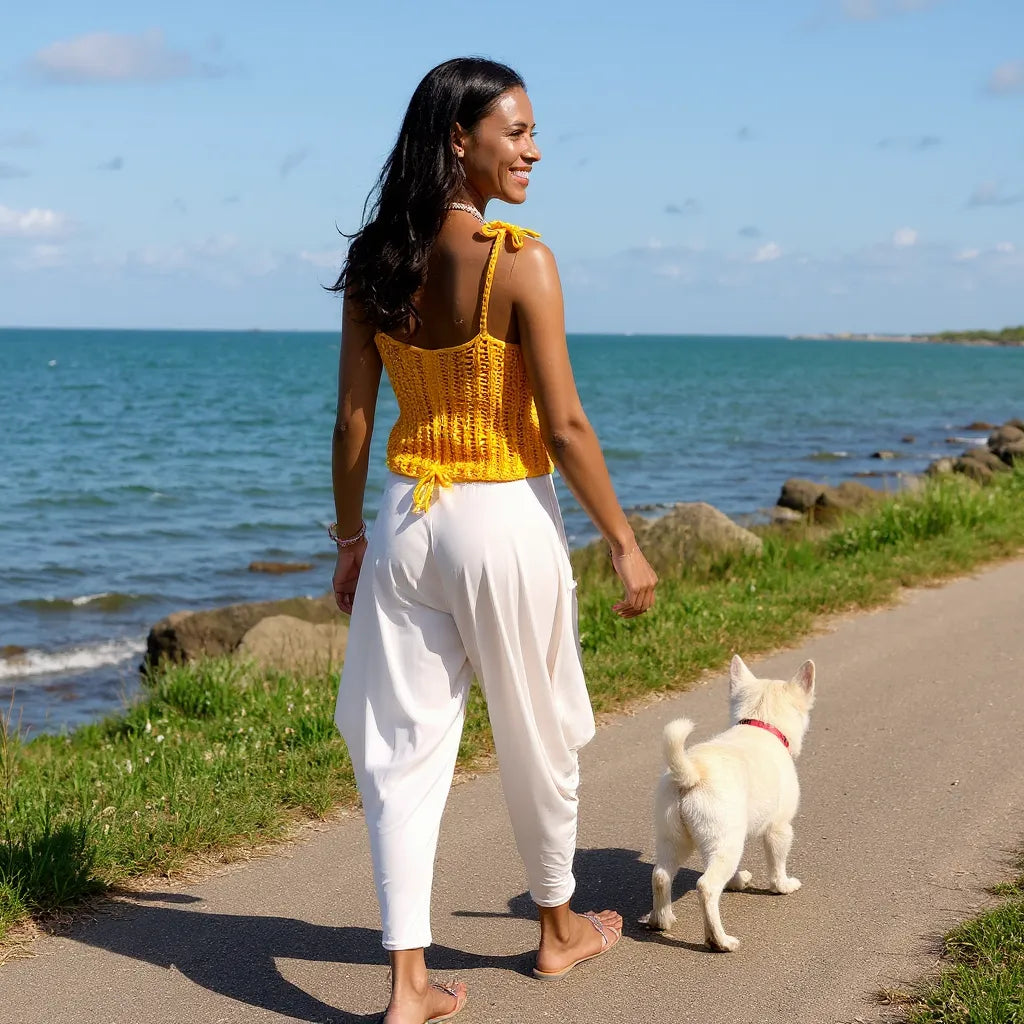 Top au crochet Aldentissimo de Cachalabibi - vue de dos d'une femme qui se promène pieds nus avec son chien près de la mer