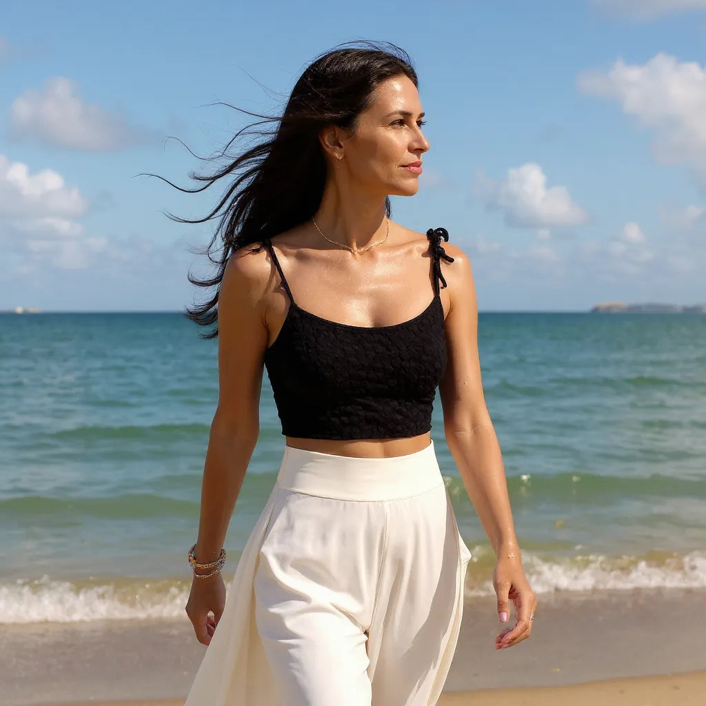 Top au crochet Blackino de Cachalabibi - vue de face d'une jeune femme cheveux au vent au bord de la mer