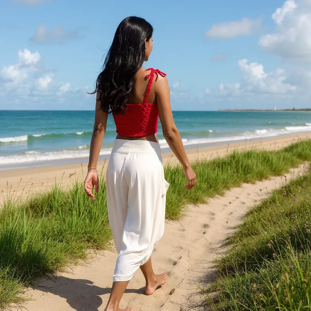Top au crochet Marsianne de Cachalabibi - vue de dos d'une jeune femme marchant sur un sentier longeant une plage
