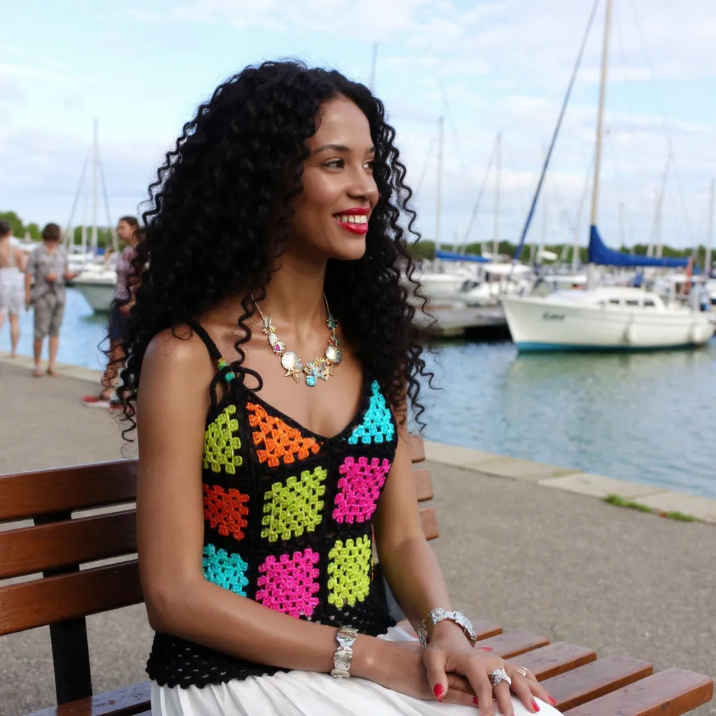 Top au crochet Quadrato de Cachalabibi - vue de face d'une jeune femme assise sur un banc dans une marina