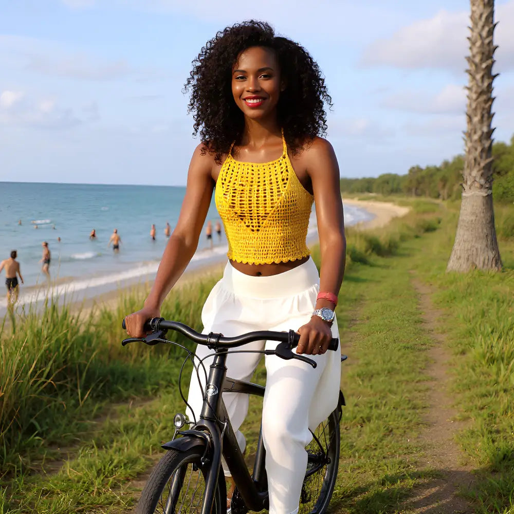 Top dos nu au crochet Giallo de Cachalabibi - vue de face d'une jeune femme à vélo le long de la mer