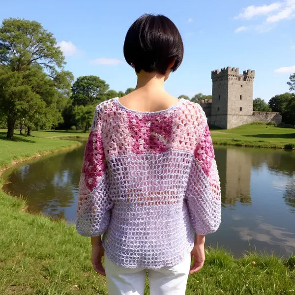 Tunique au crochet Lupina de Cachalabibi - vue de dos d'une jeune femme près d'un étang et d'une ruine de château